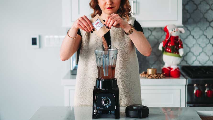 A woman putting something into a blender