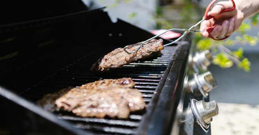 Man grilling meat on a gas grill
