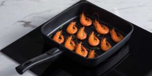grill pan on electric stove having shrimps in it