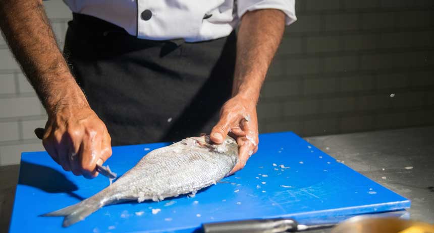 a chef cutting fish with a fillet knife