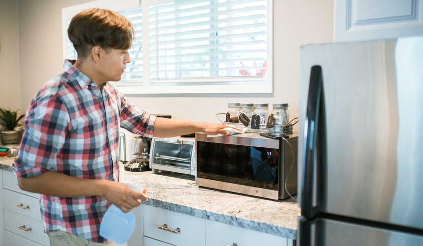 boy cleaning microwave in a kitchen