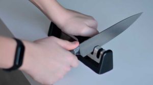 a teenager sharpening a knife with electric knife sharpener