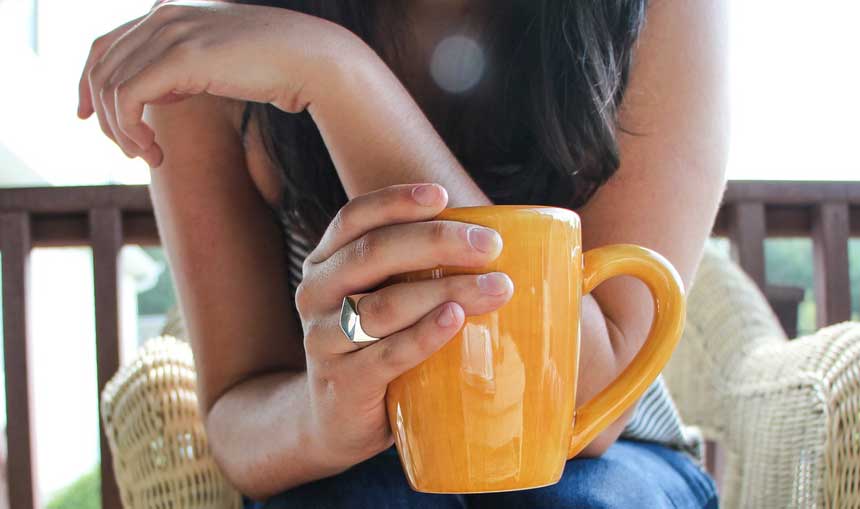 close up of a girl holding yellow coffee mug