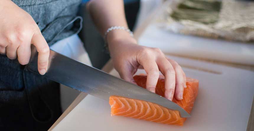 woman cutting meat piece with a large knife