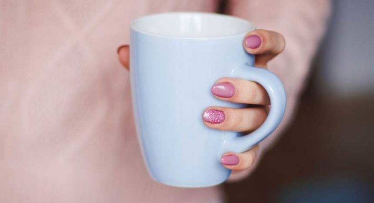 girl wearing pink dress holding a white mug of coffee