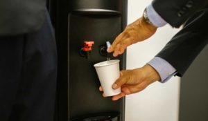 Man filling a cup from a black water dispenser
