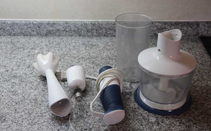 A hand blender with accessories on kitchen shelf
