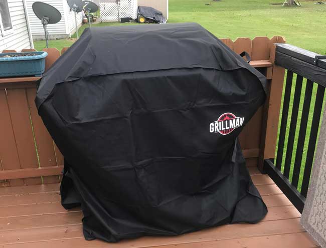 Black colored Grillman grill cover in backyard covering a gas grill