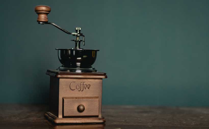 An old manual coffee grinder with coffee beans