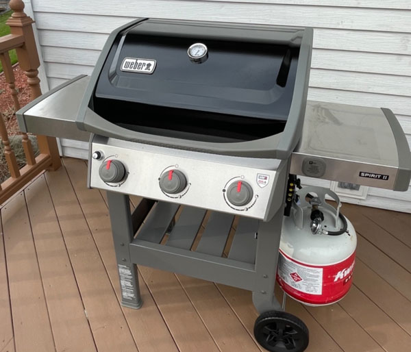 weber gas grill in backyard with a cylinder around