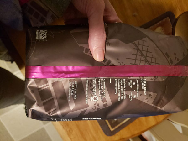 A woman holding Starbucks Coffee pack & showing back side of pack