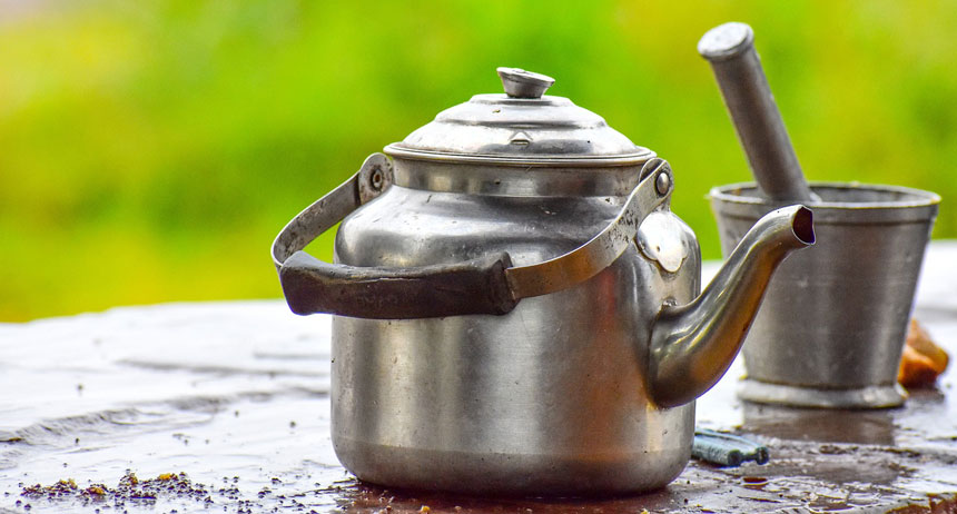 Close up of a stainless steel tea kettle with manual grinder around