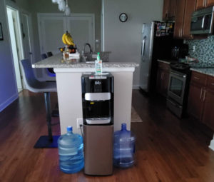 Brio bottom loading water dispenser in a kitchen with 2 gallons water around