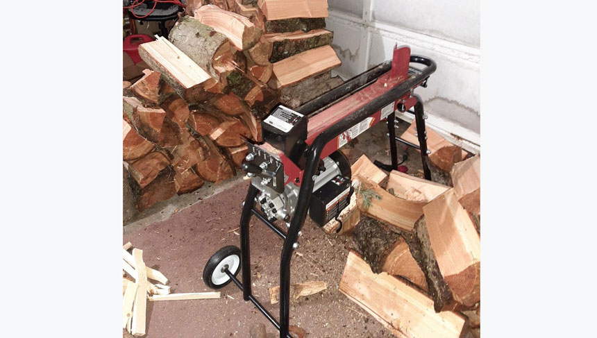 Close up of an electric wood splitter with logs around