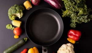 Top view of an empty frying pan with vegetables around