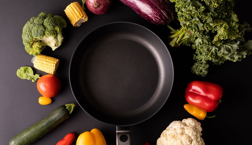 overhead-view-of-empty-frying-pan-amidst-various-vegetables-min