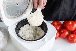 someone pouring boiled rice from rice cooker